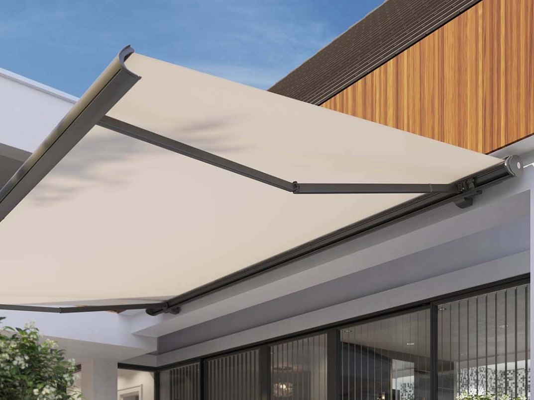 Große Gelenkarmmarkise Toscana Grande mit hellem Tuch an einem modernen Haus