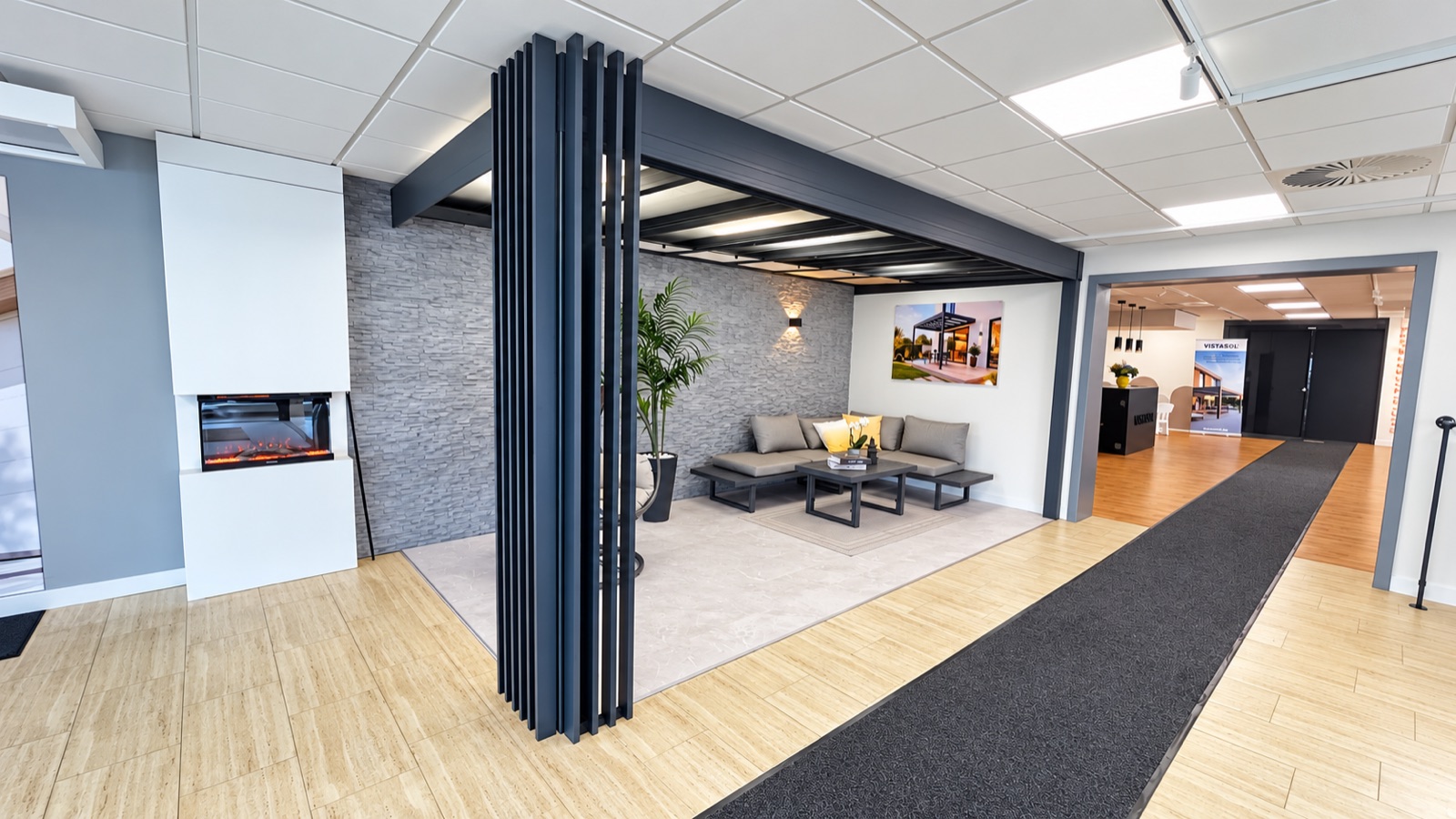 Dunkles Überdachungsmodell mit seitlichen Lamellen und Loungemöbeln im Showroom