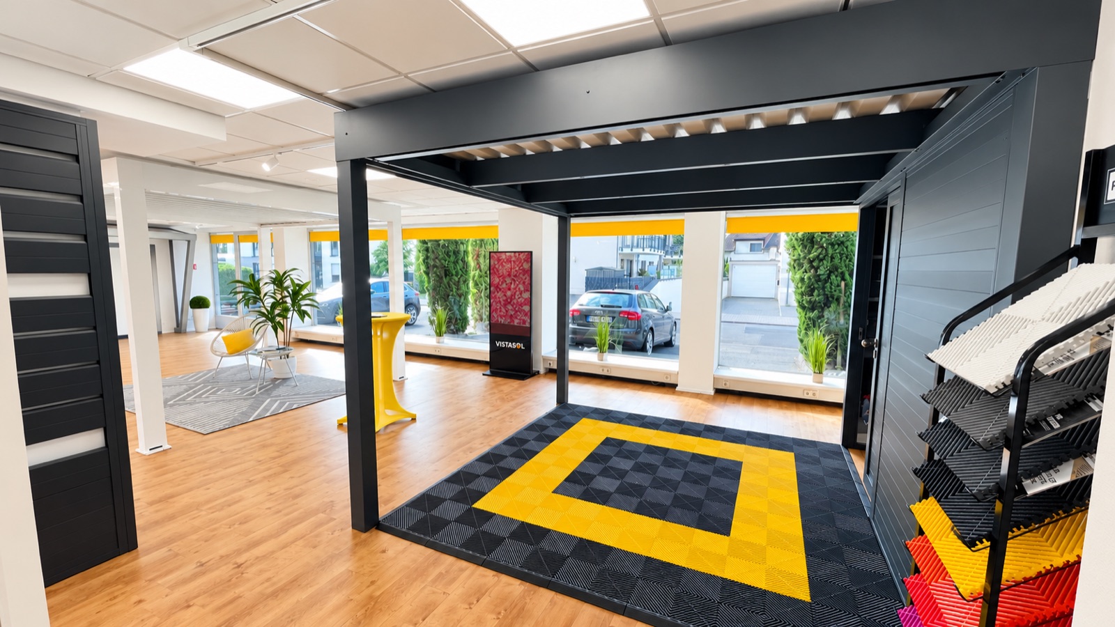 Anthrazitfarbenes Lamellendachmodell mit Seitenwand und Materialmustern im Showroom